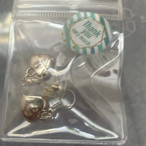 (Inte äktasilver) Silvriga örhängen med hjärtan - Snygga silvriga örhängen med hjärtformade hängen. Hjärtana har en ingraverad design som ger dem en cool och unik look. Perfekta för att lyfta vilken outfit som helst och passar dig som gillar detaljer med lite edge.