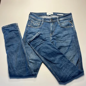Replay Anbass slim fit jeans blå - Ny pris 1900kr nu ändast 399kr Snygga blå jeans från Replay, modell Anbass med slim fit. Klassisk femficksdesign, dragkedjegylf och coola detaljer som Replay-knapp och ljus tvätt. Perfekta för dig som gillar en smalare passform och stilren look.