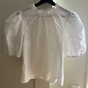 Vit blus med broderade puffärmar - Superfin vit blus med broderade detaljer och hålmönster framtill och på de puffiga korta ärmarna