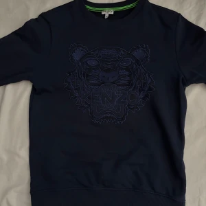 Mörkblå Kenzo sweatshirt med tiger !ÄKTA! - Snygg mörkblå sweatshirt från Kenzo med ikoniskt broderat tigerhuvud och logga på bröstet. Tröjan har rund halsringning med gröna detaljer på insidan och långa ärmar. Perfekt för dig som vill sticka ut med en klassisk streetstyle-look.