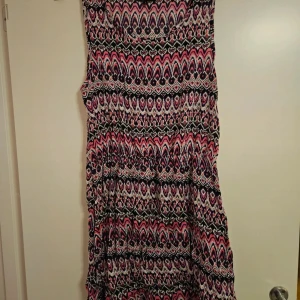 Mönstrad klänning från Bik Bok - Säljer en färgstark klänning från Bik Bok i storlek L. Klänningen har ett coolt mönster i rosa, lila, svart och vitt och är tillverkad i mjuk viskos. Modellen är ärmlös och har en avslappnad passform som ger skön vibe. Perfekt för dig som gillar att sticka ut med din stil!