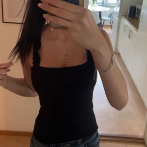 Svart topp med volangband 💕 - Snygg svart topp med raka linjer och breda axelband med volangdetalj. Perfekt att matcha med jeans eller kjol för en stilren look. Toppens material känns mjukt och följsamt mot huden. Stretchigt material passar XXS-M. pris kan diskuteras💕