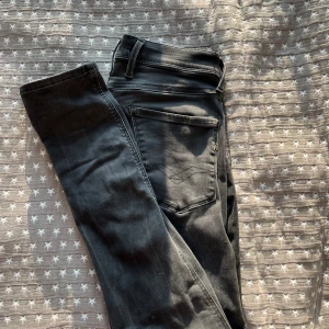 Svarta Replay Anbass jeans - Säljer ett par svarta Replay Anbass jeans i klassisk femficksmodell. Jeansen har smal passform, snygga detaljer på bakfickorna och är tillverkade i stretchig bomullsdenim för extra komfort. Bra skick utan defekter, nypris ca 1500.
