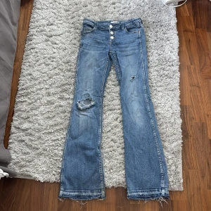 Blå bootcut jeans  - Säljer ett par blåa bootcut jeans som är lågmidjade. Dom jag egenklippta hål och är i storlek 146. Dock är dom uppsprättade längst ner som gör att dom blir några cm längre ❤️