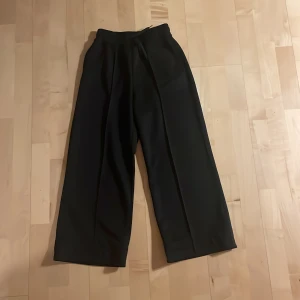 Svarta wide byxor från H&M Move - Svarta byxor från H&M Move i storlek 158/164. De har breda ben, elastisk midja med snörning och är tillverkade i ett mjukt syntetmaterial.