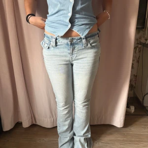 True Religion Joey ljusa bootcut jeans - Säljer ett par ljusblå True Religion Joey jeans med låg midja och bootcut. Jeansen har snygga bakfickor med lock och silverknappar samt klassisk True Religion patch bak. Tillverkade i jeansmaterial med cool tvättad look. De e köpta på NELLY för någon vecka sedan. Bara andvända cirka två gånger i storlek 27, säljer pga att de e för långa för referens är min syster på bilden 161💓 Nypris: 1300