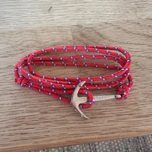 Rött armband med ankare från Blvckout - Snyggt armband med röd, blå och vit flätad snodd och ett silverfärgat ankare som lås. Perfekt accessoar för dig som gillar marina detaljer. Ny pris 399