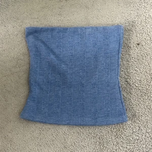 Tubtopp från H&M - Säljer en blå ribbad tubtopp från H&M i storlek XS. Toppen är bandeau-modell och har en snygg, enkel design med diskreta vertikala ränder. Perfekt för dig som gillar en stilren och bekväm look.