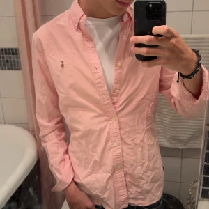 Ralph Lauren skjorta rosa - Jag säljer min jättefina rosa skjorta från Ralph Lauren. Jättefint skick, som ny och inga defekter. Perfekt för vardagen och finare tillfällen 🤩Det är bara att skriva om du är intresserad eller har någon fråga 💯