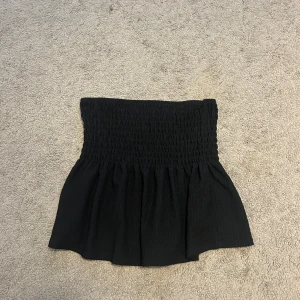 Svart tubtopp  - Säljer en svart bandeau tubtopp från Gina Tricot i storlek XS. Perfekt att styla med jeans eller kjol för en trendig look.