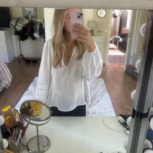 Vit blus H&M i linne - Superfin vit blus från H&M i luftig linnemix. Skjortan har v-ringning med snörning, vida långa ärmar och snygga broderade detaljer längs ärmar och framstycke. Aldrig använd