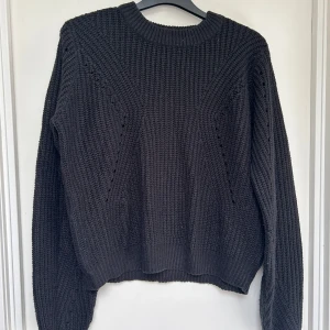 Svart stickad tröja  - Mysig svart stickad tröja med grov ribbstickning och rund hals. Tröjan har långärmade ärmar.