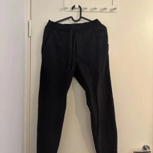 Svarta Lululemon-byxor med snörning - Säljer ett par svarta mjukisbyxor med elastisk midja och snörning framtill. Storleken ses på bild 3&4. Två fickor fram en ficka bak. 