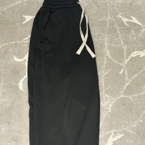 Svarta mjukisbyxor med snörning - Svarta mjukisbyxor med elastisk midja och vit snörning. Byxorna har en avslappnad passform och är perfekta för chill dagar. Tillverkade i mjukt material för extra komfort.