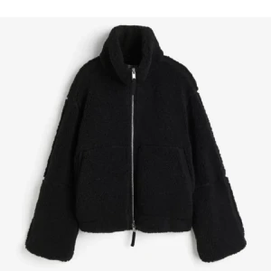 Svart teddyjacka hm - Mysig svart teddyjacka med hög krage. Jackan har en rak, lite oversized passform och stängs med en silverfärgad dragkedja. Som sagt från hm och är helt slutsåld