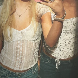 Vit/grå spetsig topp från Nelly - Supersöt vit-grå topp från Nelly💓 med spetsdetaljer och v-ringning. Topp med korta ärmar, genombrutet spetsmönster och figurnära passform. Perfekt för allt från festliga till vardagligare tillfällen💝💝