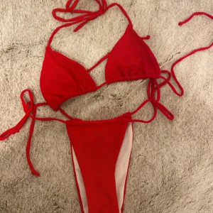 Rött bikini set  - Rätt bikini sett från shein. I gott skick. Strong modell som man kan knyta på sidorna. Hör av er vid frågor och fler bilder. Passar mig som har storlek S i bikini topp och S i bikini botten. Justerbara band till toppen. Inga inlägg i toppen.