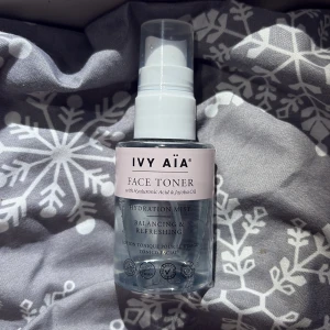 IVY AÏA Face Toner Hydration Mist - Fräsch ansiktsmist från IVY AÏA med hyaluronsyra och jojobaolja. Tonern kommer i en genomskinlig plastflaska med sprayfunktion och har en ljusrosa etikett. Perfekt för att återfukta och balansera huden snabbt.