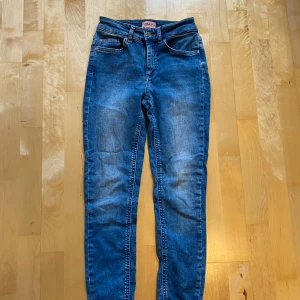 Blå skinny jeans från ONLY, S/32 - Snygga blå jeans från ONLY i klassisk femficksmodell. Jeansen har skinny passform och normal midja, med en fräsch tvätt och subtila slitningar. Materialet är mjukt jeans-tyg som sitter skönt och följer kroppen. Perfekta för dig som gillar en smal siluett.
