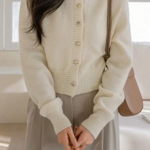 Beige kofta med pärlknappar - Superfin beige kofta med rund hals och dekorativa pärlknappar framtill. Tröjan är stickad i mjukt material och har breda ribbade muddar vid ärmslut och nederkant. Perfekt för lager-på-lager och ger en clean, stilren look.