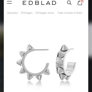 Peak Creoles S Steel örhängen från Edblad - Coola örhängen i silverfärgat stål från Edblad med spetsiga nitar runt hela ringen. Perfekta för dig som vill ha en edgy och modern stil. Säljs som ett par. De är helt nya och endast använda 1 gång. Kände inte att dess svar just min smak på örhängen. Det är den ”stora” storleken på Edblad 