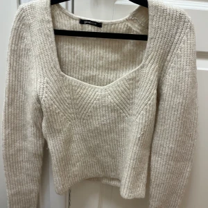 Beige stickad croppad tröja från Gina Tricot - Säljer en jätte snygg beige stickad tröja från Gina Tricot med croppad passform och lång ärm. Tröjan har en snygg v-ringad halsringning och ribbad struktur. Perfekt för lager-på-lager under höst och vinter. har nog bara kommit till andvändning 1 gång