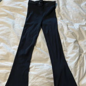 Svarta ribbade bootcut-byxor - Svarta bootcut-byxor med ribbad struktur och hög midja. Byxorna har en figurnära passform upptill och utsvängda ben nertill. Perfekta att styla med en crop top eller hoodie.