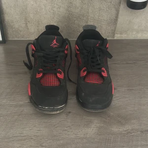 Svarta och röda Nike Air Jordans - Säljer ett par svarta och röda Nike Air Jordans med klassisk siluett och Jumpman-logga på plösen och hälen. Skorna har snörning, meshdetaljer och platt sula. Perfekta för dig som gillar streetwear och vill sticka ut med snygga färgdetaljer.