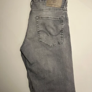 Gråa Slimfit jeans från Jack & Jones - Ett par gråa slimfit jeans från Jack & Jones i storlek 29/30. Dom är gjorda i ett mjukt denim tyg vilket gör dom väldigt bekväma och vardagliga. Dom är sparsamt andvända och är köpta för 900kr hos Jack & Jones