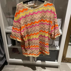 Mönstrad tröja från Missoni - Säljer en färgglad tröja från Missoni med vågigt mönster i orange, rosa, gul och beige. Tröjan har trekvartsärm och är tillverkad i ett lätt, stickat material. Perfekt för dig som gillar unika plagg med mycket färg. Pris är disskutetbart💕