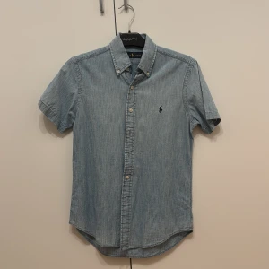 Ljusblå kortärmad skjorta från Ralph Lauren - Säljer en ljusblå kortärmad skjorta från Ralph Lauren i jeansliknande bomullstyg. Väldigt bra skick.