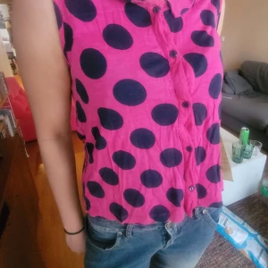 Rosa ärmlös topp / linne  med stora blå prickar - Säljer en rosa ärmlös prickig topp med stora blå prickar och knappar fram. Linnet  har en liten krage och är från en äldre kollektion från Monki. Storlekn M.