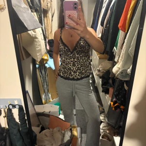 Leopardmönstrad linnetopp med spets - Säljer en snygg leopardmönstrad linnetopp med svarta spetsdetaljer längs urringning och nederkant. Toppen har smala axelband och v-ringad hals. Banden är även justerbara. Helt ny, köpte men använde inte. Skriv för fler bilder eller info🥰