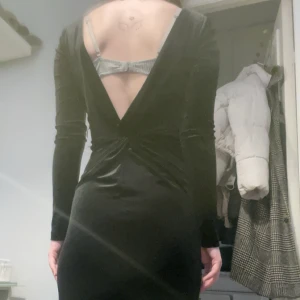 Svart sammetsklänning med slits från Gina Tricot - Säljer en lång svart sammetsklänning från Gina Tricot. Klänningen har lång ärm, hög slits framtill och en snygg öppen rygg. Perfekt för dig som vill sticka ut med en elegant och stilren look.