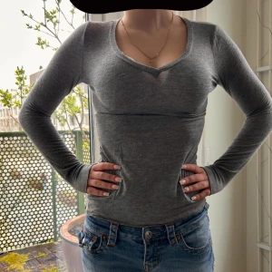 Grå långärmad topp med v-ringning - Säljer en grå långärmad topp med v-ringning. Modellen är tight och har en enkel, stilren design som passar perfekt till jeans. Mjuk och skön kashmirmix, perfekt för vardagslooken. Använd 2 gånger, nytt skick från intimissimi. inköps pris: 569kr.
