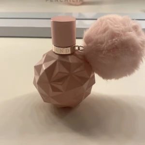Ari by Ariana Grande Eau de Parfum - Säljer en söt parfymflaska från Ariana Grande, Ari. Flaskan är ljusrosa med geometriskt mönster och har en fluffig rosa boll som dekoration. Perfekt för dig som gillar feminina och lekfulla dofter. Säljer den då den ej kommer till användning. Nästan hela flaska är full. Har några enstaka repor på flaskan men ingen som försämrar parfymen. Kanske ca 40-45 ml kvar.