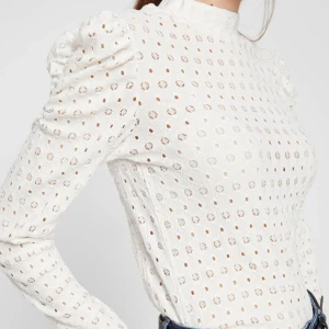 Vit blus med puffärm från Pieces - Säljer en vit blus från Pieces med hög hals och långa puffärmar. Blusen har broderade hålmönster över hela tyget och rynkade axlar för extra volym. Perfekt att styla med jeans eller kjol. Endast använd fåtal gånger🩷🩷
