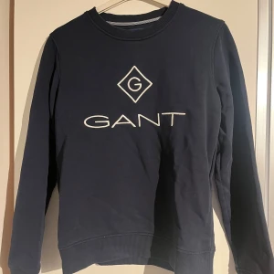 Mörkblå sweatshirt från GANT - Säljer en mörkblå sweatshirt från GANT med vit broderad logga på bröstet. Endast använd fåtal gånger 
