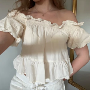 Offshoulder volangtopp - Säljer en söt offshoulder topp i vitt med volangdetaljer. Toppen har korta puffärmar 💕💕! Passar både S och xs även möjligen M