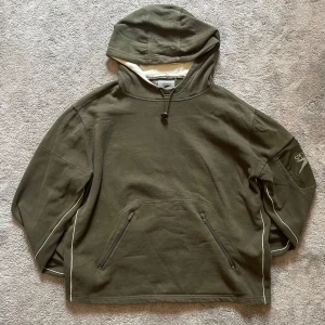 Olivgrön hoodie från Speedo - Olivgrön hoodie från Speedo med huva och dragkedjeförsedda fickor framtill. Tröjan har vita detaljer längs ärmarna och en Speedo-logga på ena ärmen. Perfekt för aktiviteter och sport. Öppen till alla offers‼️‼️