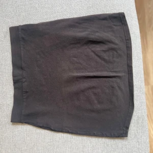 Svart kortkjol från H&M.S - En enkel svart kortkjol från H&M i mjukt bomullsmaterial. Kjolen har en tight passform och är perfekt att matcha med olika toppar. Klassisk och stilren design utan extra detaljer.storlek passar 34-36