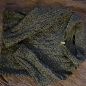 Grå stickad tröja med dragkedja från Morris - Mysig grå stickad tröja från bik bok med kabelstickat mönster och dragkedja vid halsen. Perfekt för kyliga dagar och enkel att matcha med olika outfits. Knappt använd så den är som ny 🩵