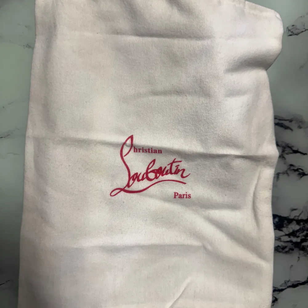 Säljer ett par gråa sneakers från Christian Louboutin med ovandel i mocka och klassisk röd sula. Skorna har snörning och vit platt sula, perfekt för dig som gillar exklusiva detaljer och stilren design. 100kr extra med box. 1 av 1. Kengät.