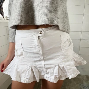 Vit volangkjol  - Söt vit kort kjol med volangkant och två framfickor. Jätte fint skick, skulle säga att den passar i längd om man är mellan 160-170 cm