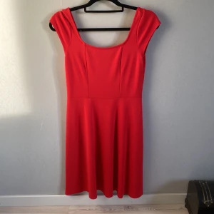 Röd klänning med korta ärmar - Snygg röd klänning med korta ärmar och rund halsringning. Perfekt för en somrig look. Klänningen har en enkel och stilren design som passar många tillfällen. Ny och oanvänd stl S.