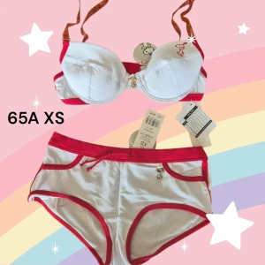 Vit och röd set med bh och trosor Snoopy - Säljer ett sött set med vit och röd bh och matchande trosor med Snobben / Snoopy på. Bh:n har uttagbara inlägg och justerbara axelband med en liten charm framtill. Trosorna har röda kanter och en dekorativ rosett. Perfekt för en färgglad och lekfull stil! Oanvända med prislappen kvar. Finns fler annonser med möjlighet till bundle med rabatt. Kom med prisförslag.