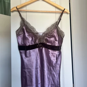 Lila linne från xanaka - Ett lila siden linne från Xanaka. Bruna detaljer i form av spets och en rosett. Storleken är okänd men uppskattar den till en s eller liten m.