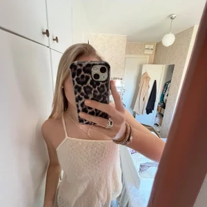 Vit ärmlös linnetopp - Säljer en stilren vit ärmlös linnetopp med smala axelband. Toppen har en enkel och luftig design, perfekt för varma dagar. Någon småfläck och sliten söm men syns knappt!