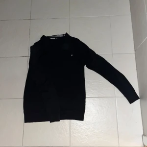 Svart tröja från J.Lindeberg - Snygg svart tröja från J.Lindeberg med rund hals och diskret logga på bröstet. Perfekt för en stilren look. Finns även i marinblå 