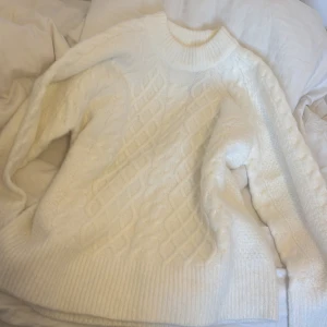 Vit stickad tröja från 157 - Säljer en mysig vit stickad tröja från 157. Tröjan har ett snyggt kabelstickat mönster på framsidan och ribbade muddar vid ärmslut och nederkant. Perfekt för kyliga dagar!💕